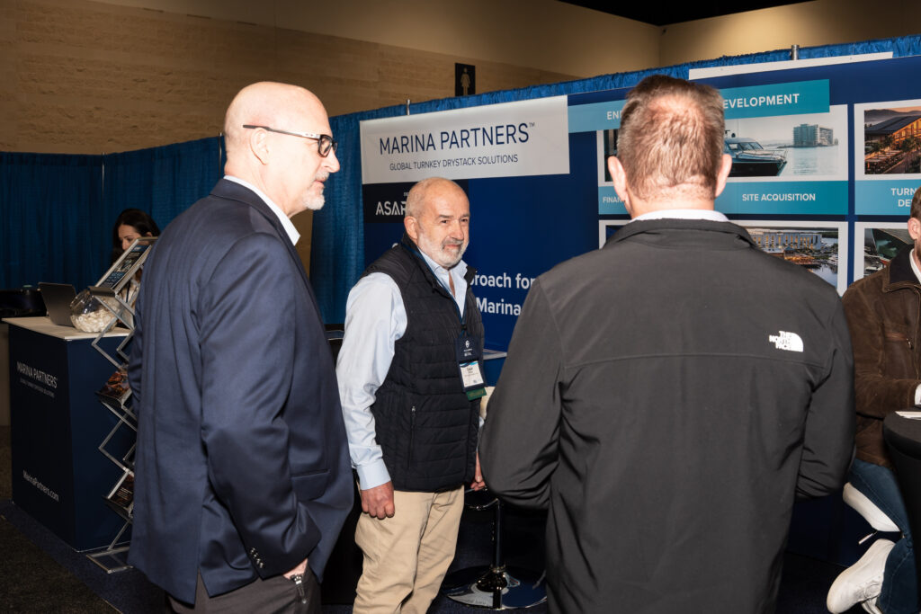 Three men talking at a trade show booth, actively engaging with each other and potential customers.