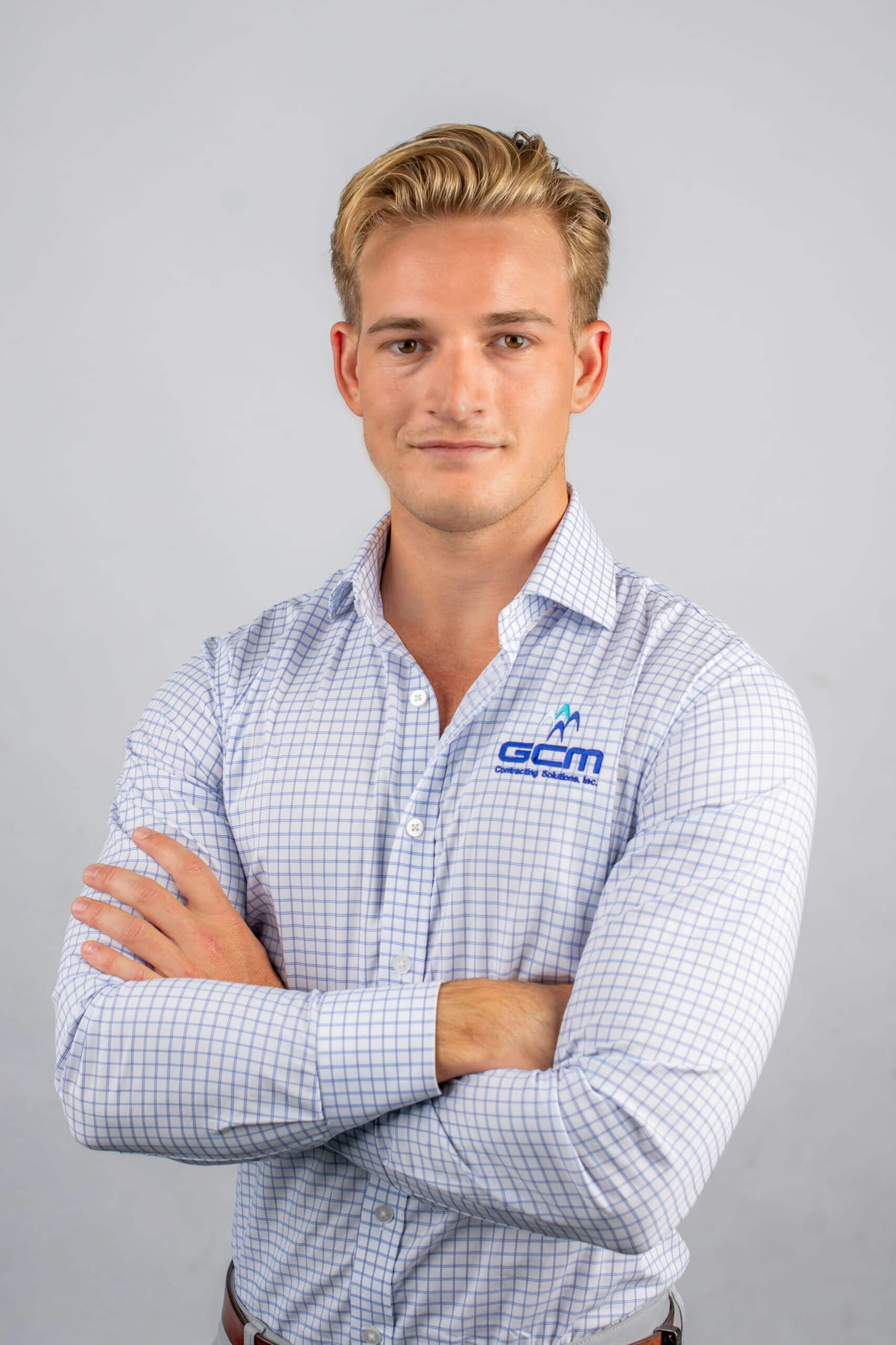 A man in a shirt and tie stands with his arms crossed, exuding confidence and professionalism.
