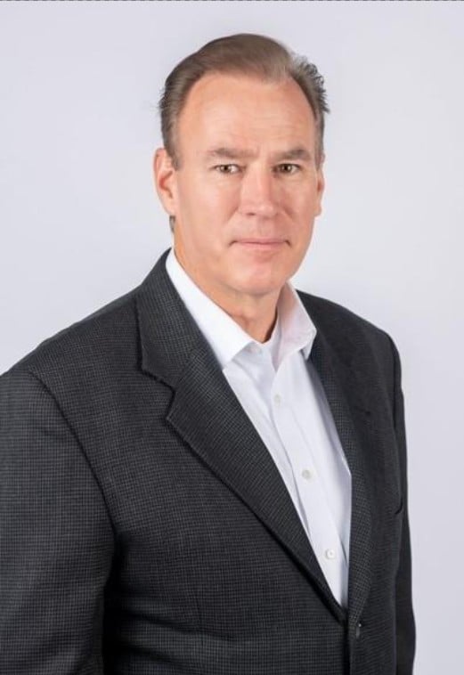 A man in a shirt and tie stands with his arms crossed, exuding confidence and professionalism.