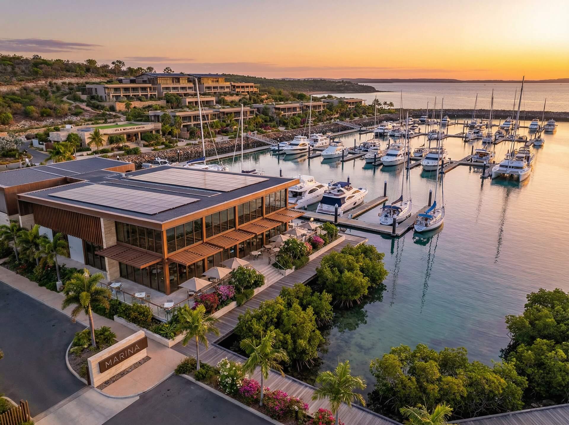 Sunset over a marina at a resort, with boats gently bobbing in the water and vibrant colors filling the sky.