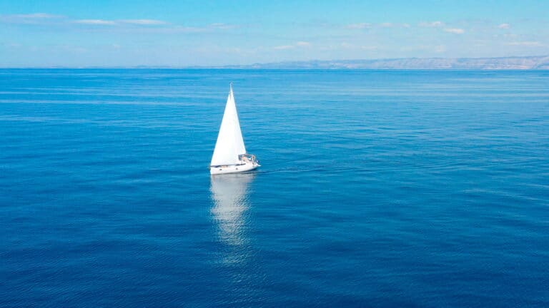 A white sailboat in the middle of the ocean