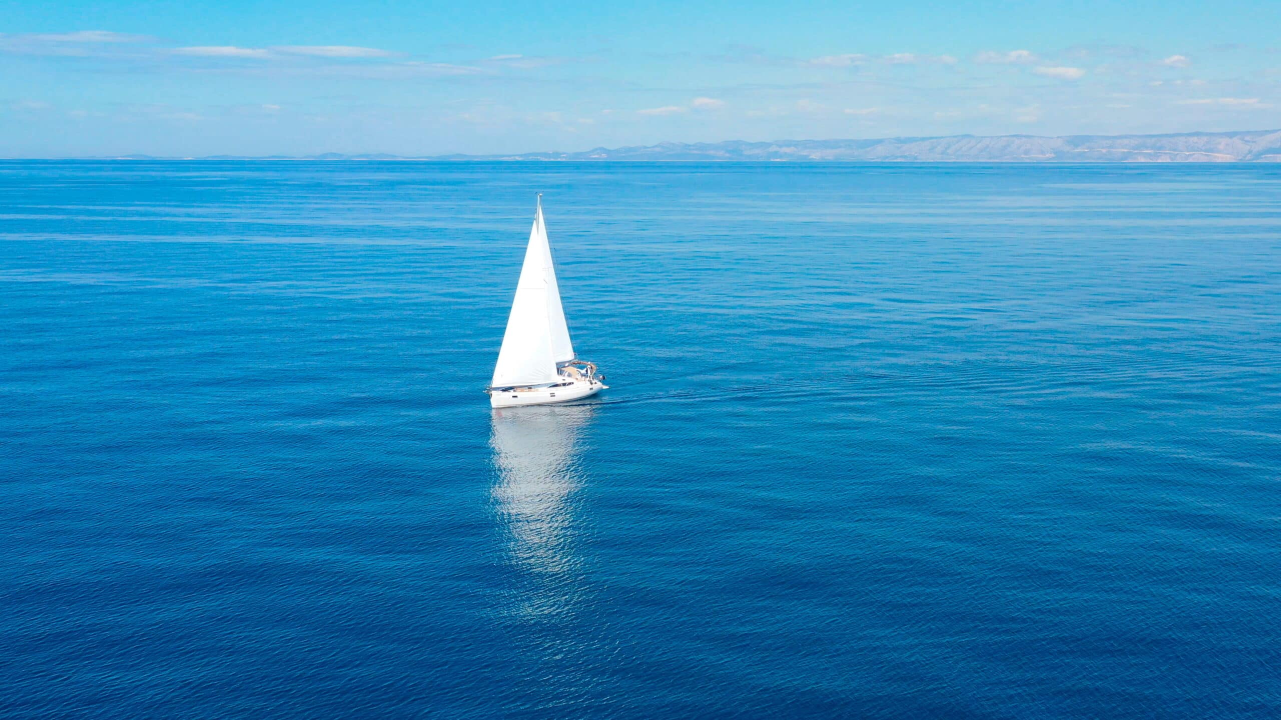 A white sailboat in the middle of the ocean